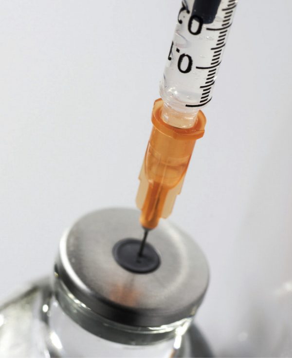 Insulin syringe puncturing a vial of compounded semaglutide for dose administration
